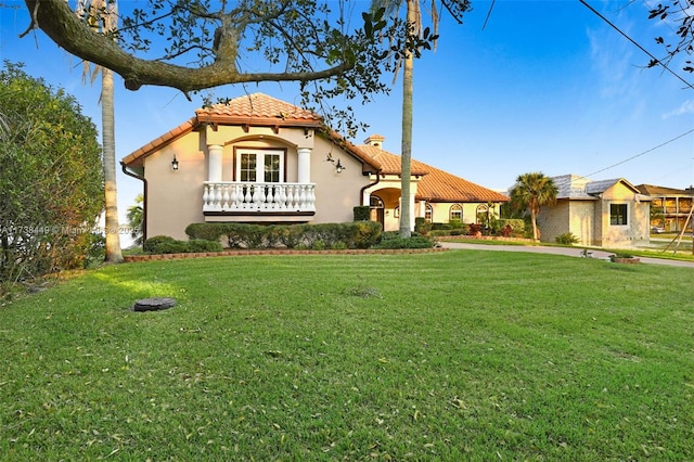 mediterranean / spanish home featuring a front lawn and french doors