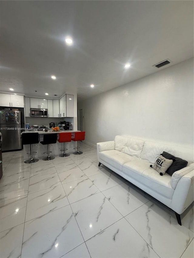 living area featuring recessed lighting, visible vents, and marble finish floor