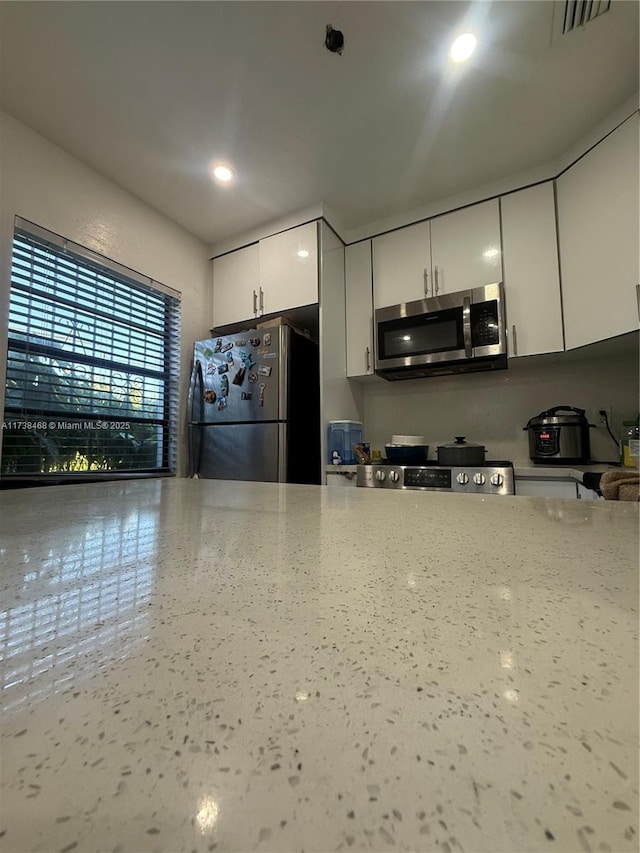 kitchen featuring white cabinetry, light stone countertops, and stainless steel appliances