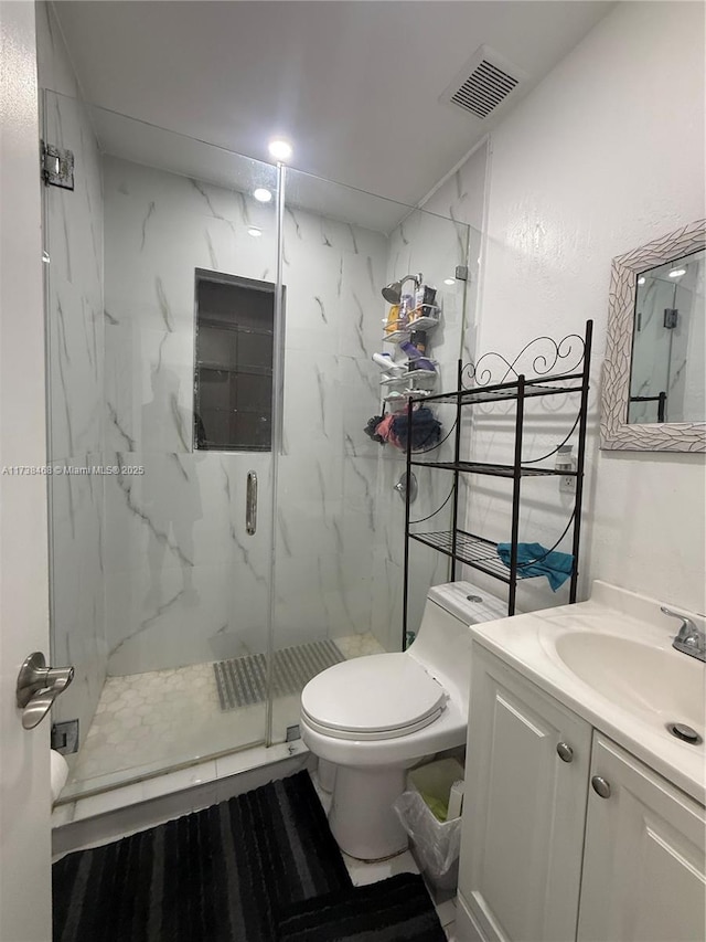 bathroom featuring a shower with door, vanity, and toilet