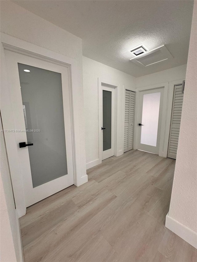 hallway featuring a textured ceiling and light hardwood / wood-style flooring