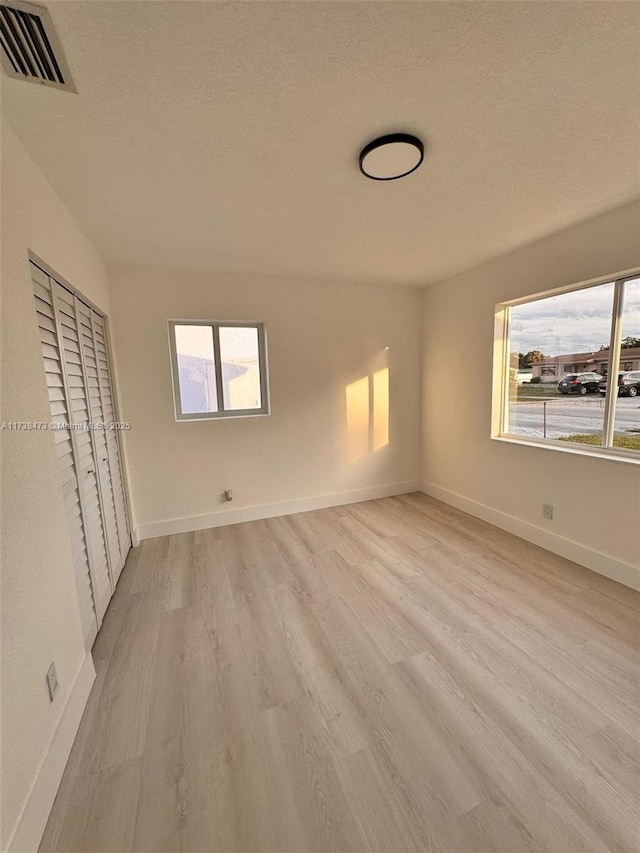 unfurnished bedroom with light hardwood / wood-style flooring, a closet, and a textured ceiling