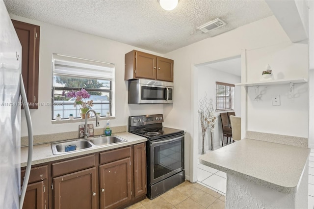 kitchen featuring stainless steel appliances, sink, light tile patterned floors, and a textured ceiling