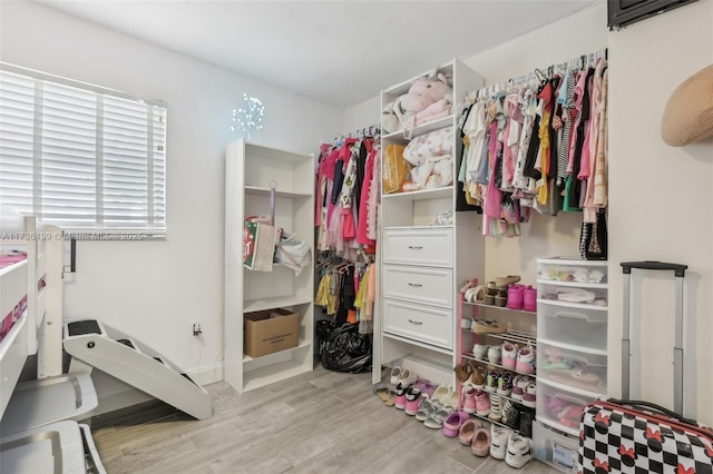 walk in closet with light hardwood / wood-style floors