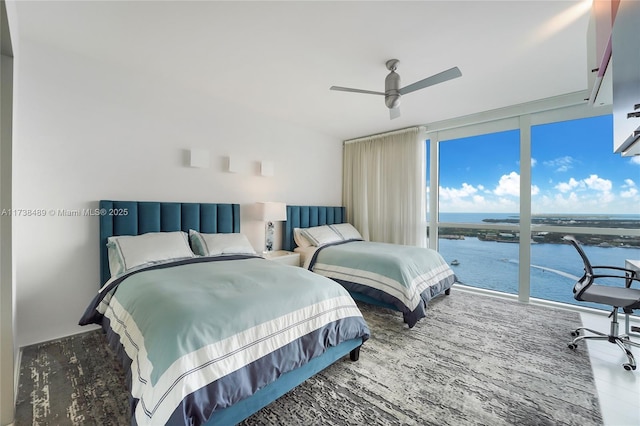 bedroom featuring a water view, ceiling fan, and floor to ceiling windows