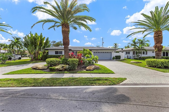 ranch-style house with decorative driveway, a garage, and a front lawn