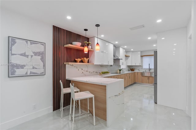 kitchen with a breakfast bar area, tasteful backsplash, white cabinets, decorative light fixtures, and kitchen peninsula