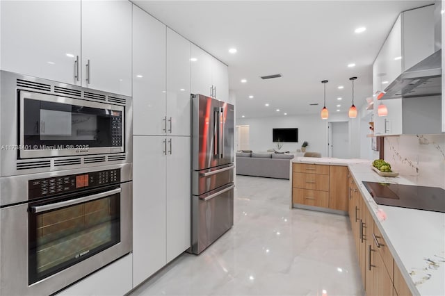 kitchen with white cabinetry, appliances with stainless steel finishes, light brown cabinetry, and wall chimney exhaust hood