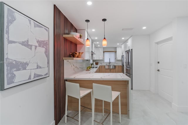 kitchen featuring a peninsula, open shelves, high end fridge, a sink, and white cabinets