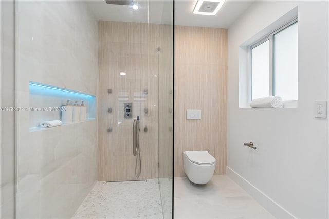 bathroom with a tile shower and toilet