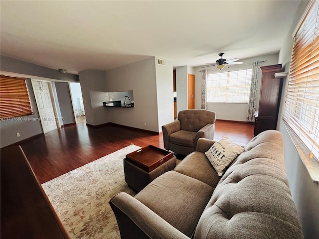 living area with baseboards, dark wood-style flooring, visible vents, and a ceiling fan