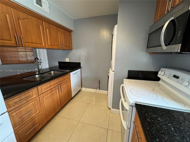 kitchen featuring range with two ovens, stacked washer and clothes dryer, light tile patterned floors, and ceiling fan