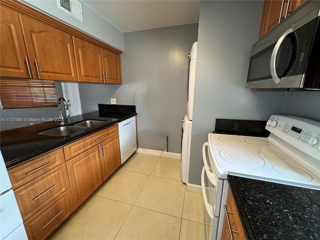 kitchen featuring white electric range, a sink, brown cabinets, dishwasher, and stainless steel microwave