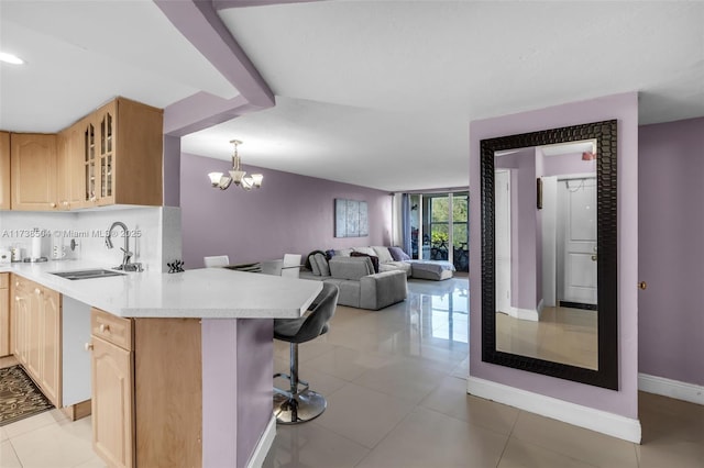 kitchen with sink, a kitchen bar, hanging light fixtures, light tile patterned floors, and light brown cabinets