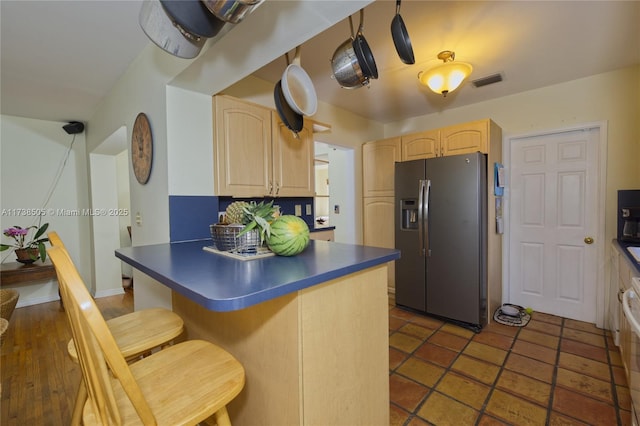 kitchen featuring stainless steel refrigerator with ice dispenser, stove, a kitchen breakfast bar, and light brown cabinets