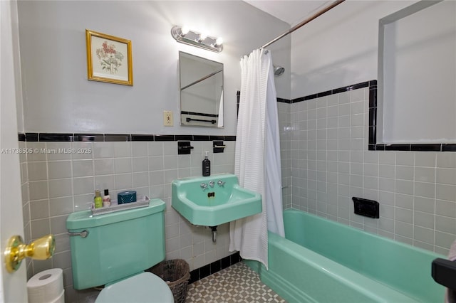 full bathroom featuring toilet, sink, shower / bath combo with shower curtain, and tile walls