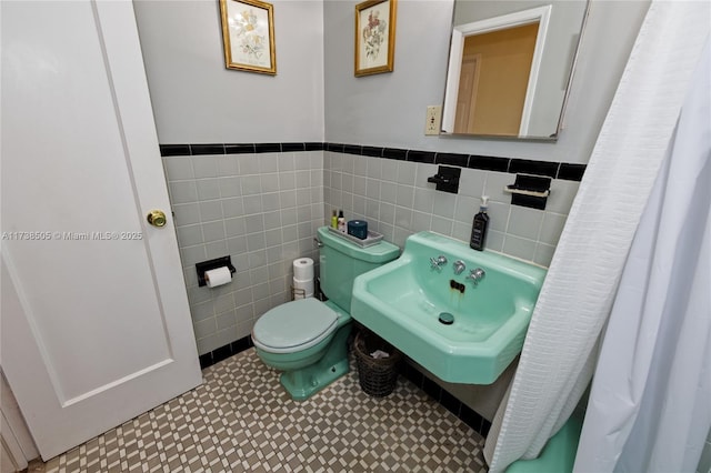 bathroom featuring toilet, sink, and tile walls