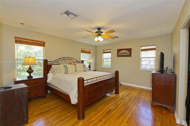 bedroom featuring ceiling fan, light hardwood / wood-style floors, and multiple windows