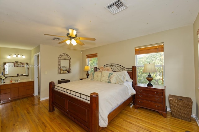 bedroom with multiple windows, sink, and light hardwood / wood-style floors