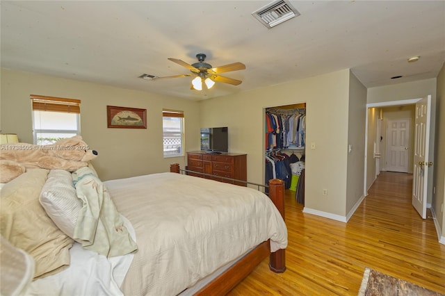 bedroom featuring a walk in closet, light hardwood / wood-style flooring, a closet, and ceiling fan