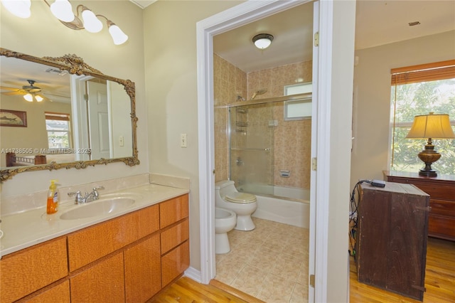 full bathroom featuring shower / bath combination with glass door, vanity, ceiling fan, toilet, and a bidet