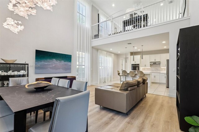 living room featuring a towering ceiling, a chandelier, and light wood-type flooring