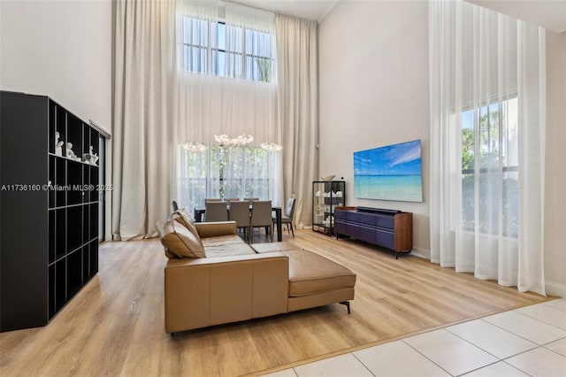 living room with an inviting chandelier, a towering ceiling, and light hardwood / wood-style floors