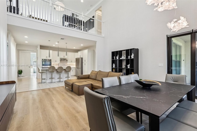 dining space featuring a towering ceiling and light hardwood / wood-style floors