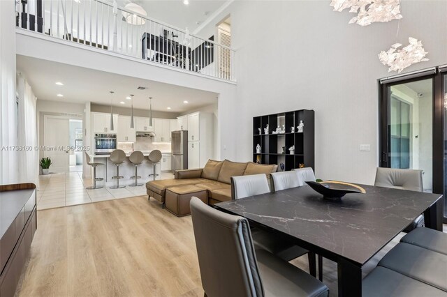 dining space featuring a high ceiling and light hardwood / wood-style floors