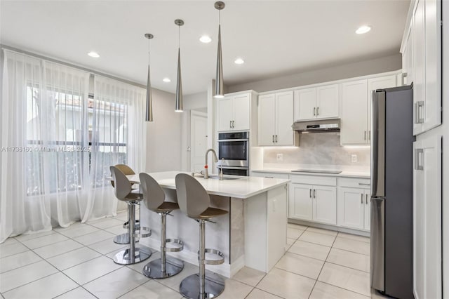 kitchen featuring decorative light fixtures, white cabinetry, an island with sink, light tile patterned floors, and stainless steel appliances