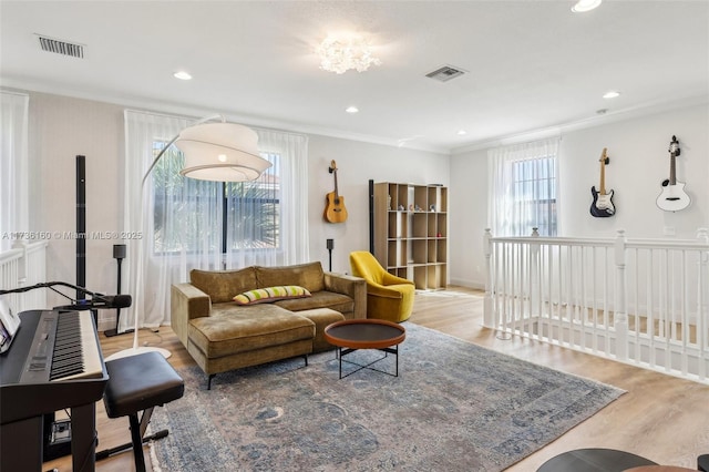 living room featuring ornamental molding, plenty of natural light, and light hardwood / wood-style flooring