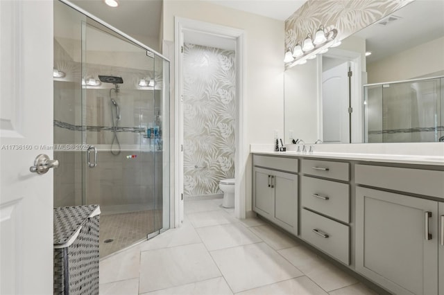 bathroom with tile patterned flooring, vanity, toilet, and walk in shower