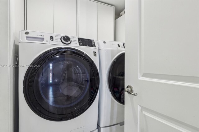 clothes washing area with cabinets and washing machine and clothes dryer