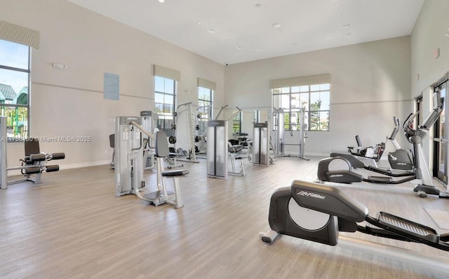 workout area with a towering ceiling and light hardwood / wood-style floors