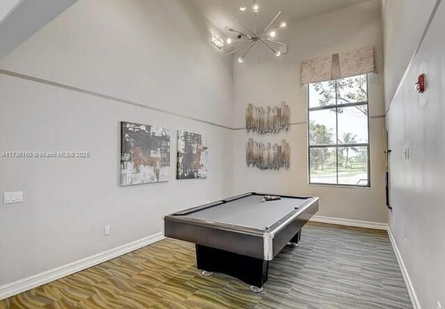 recreation room with pool table, a chandelier, hardwood / wood-style floors, and a high ceiling