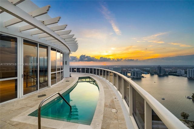 pool at dusk featuring a water view