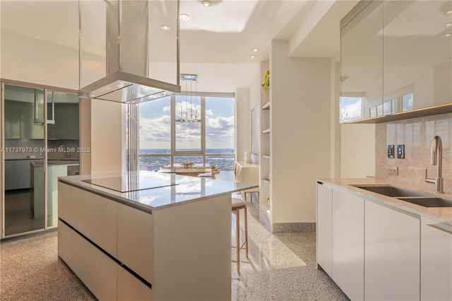 kitchen with white cabinetry, sink, a kitchen breakfast bar, island exhaust hood, and black electric stovetop