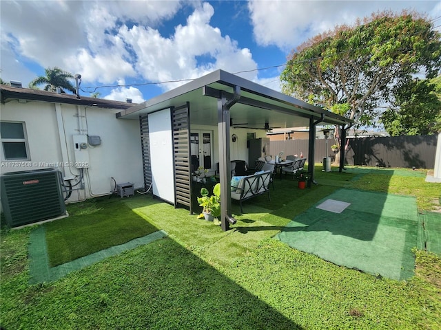 rear view of property featuring ceiling fan, a lawn, and central air condition unit