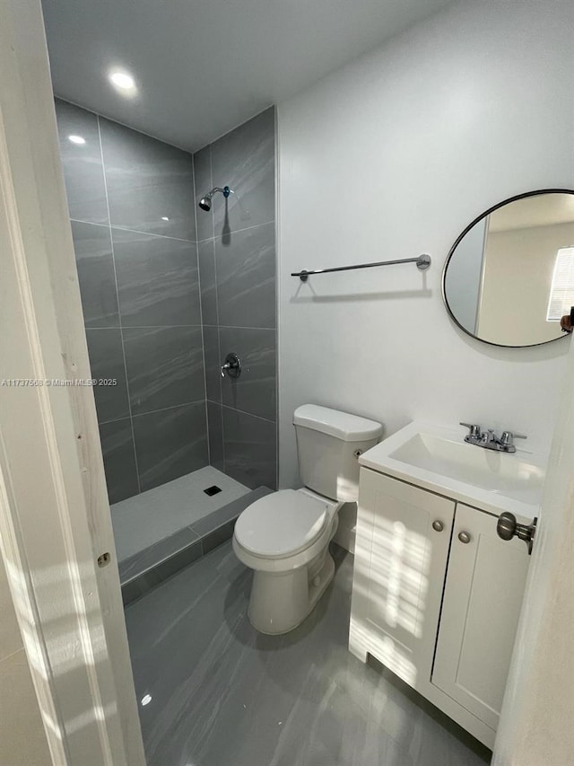 bathroom featuring vanity, toilet, and a tile shower