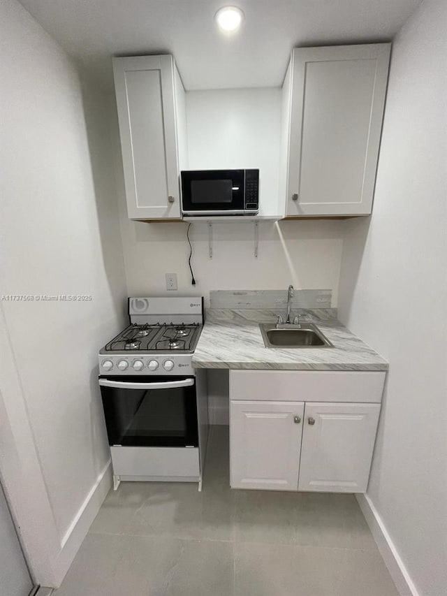 kitchen with white cabinetry, gas stove, sink, and light stone counters