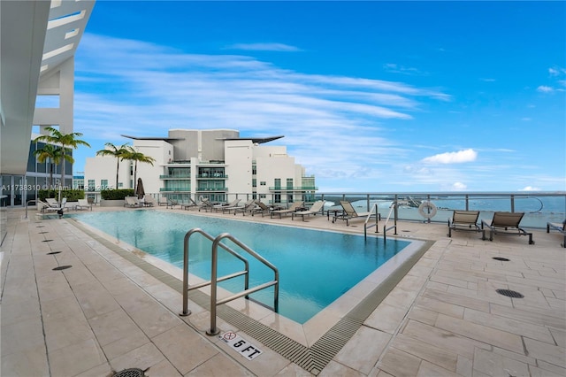 view of swimming pool with a patio and a water view