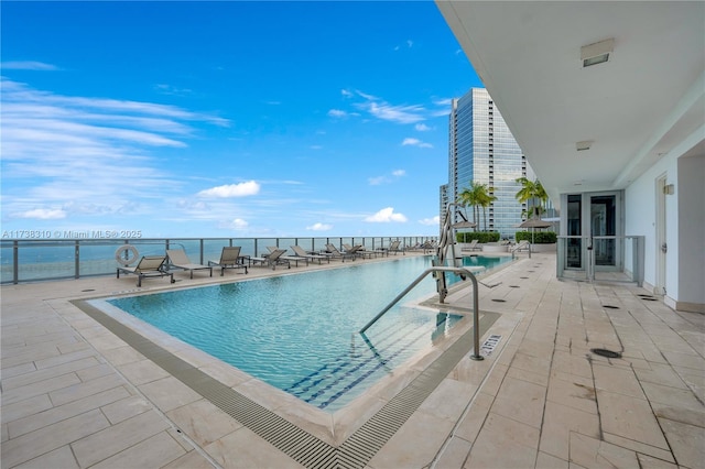 view of swimming pool featuring a water view and a patio area