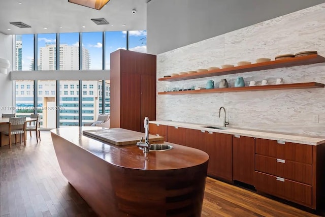 bar with tasteful backsplash, sink, dark wood-type flooring, and a wall of windows