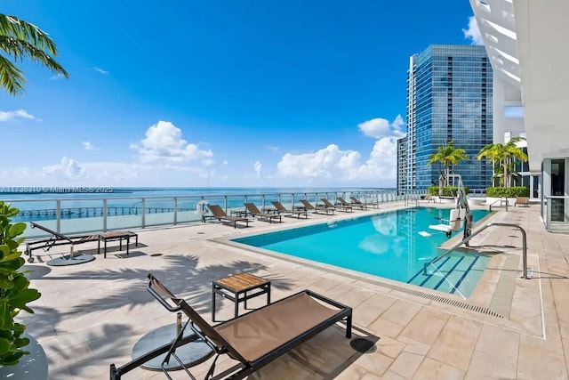 view of swimming pool with a patio area and a water view