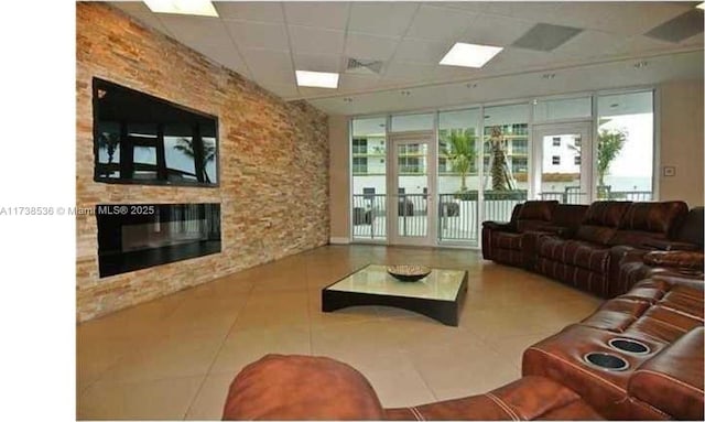 tiled living room with a paneled ceiling and a fireplace