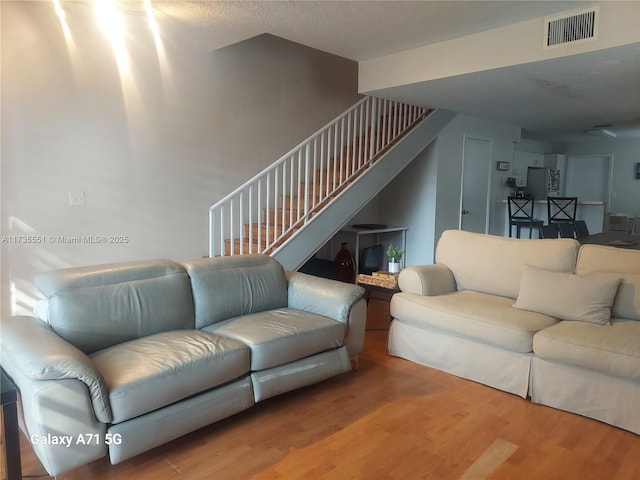 living area featuring stairs, wood finished floors, and visible vents