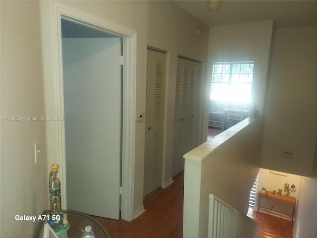 hallway with an upstairs landing and wood finished floors