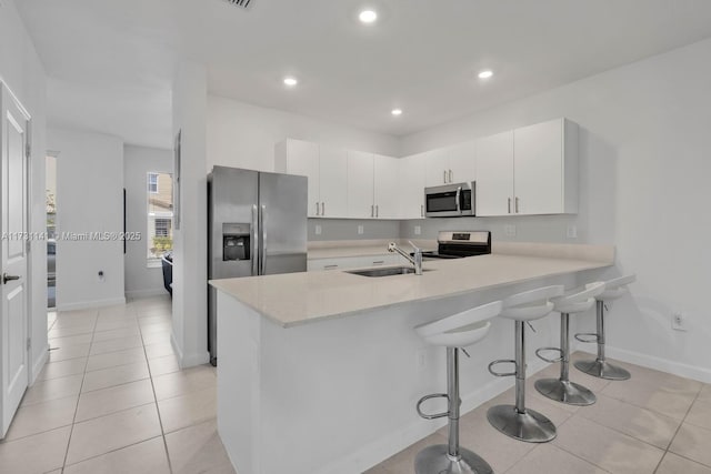 kitchen with white cabinetry, sink, stainless steel appliances, and a kitchen breakfast bar