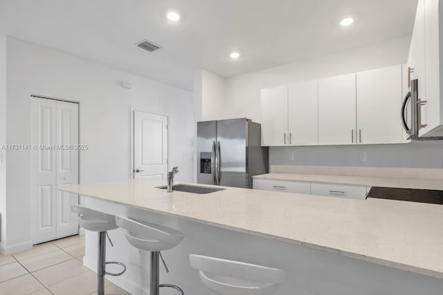 kitchen with white cabinetry, sink, stainless steel appliances, and a kitchen bar