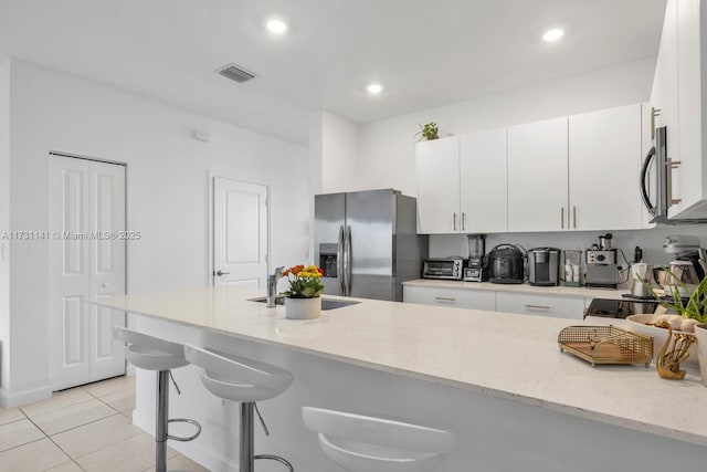 kitchen featuring white cabinetry, appliances with stainless steel finishes, light stone countertops, and sink